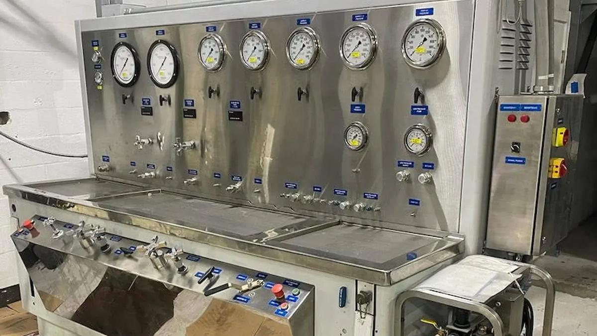 This photograph showcases a hydraulic test bench, an industrial machine with analog gauges and valves, designed for hydraulic testing purposes